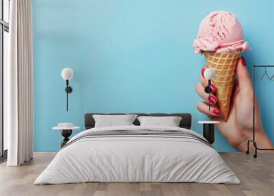 Ice cream cone on a blue background. The woman holding the ice cream by hand Wall mural