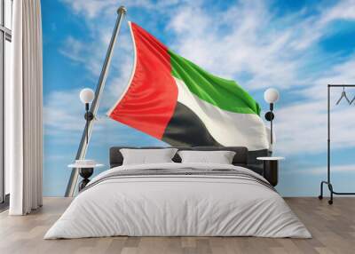 United Arab Emirates flag waving in the wind on flagpole. United Arab Emirates flag waving a blue cloudy sky Wall mural