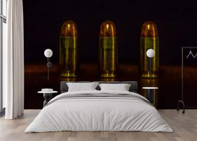 Three 45 caliber pistol cartridges aligned with reflection on the table and listening in the background Wall mural