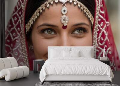 A close up of a woman adorned in traditional Indian attire. She wears a vibrant red saree with intricate white patterns Wall mural