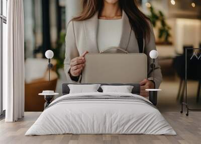 Elegant woman holding a designer laptop bag in a modern co-working space, solid color backdrop, highlighting sophistication and style Wall mural