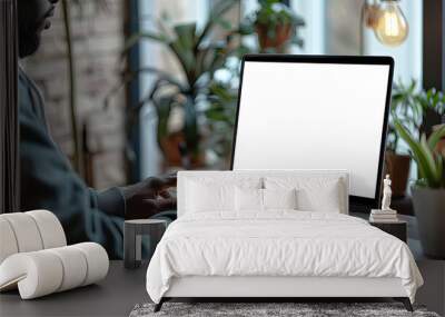 Over shoulder shot of a young man using computer laptop in front of an blank white computer screen in home Wall mural