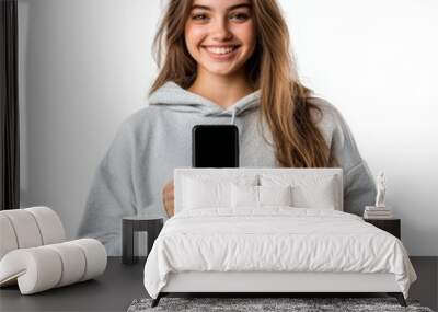 Smiling young woman in casual wear holding a smartphone isolated on white background relaxed and approachable Wall mural