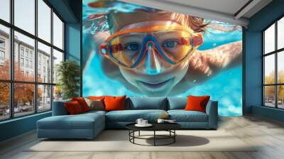 Child swimming underwater with goggles in a pool, smiling and enjoying a fun summer day, crystal clear blue water creating a vibrant and playful scene. Wall mural