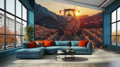 Close-up of two hands clasped together in a field, with a tractor and sunset in the background. Wall mural