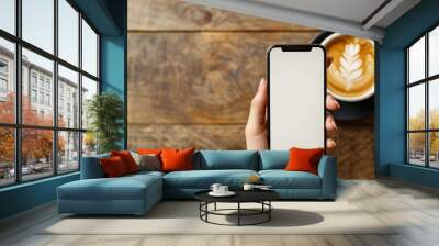 Hand Holding Smartphone with Coffee on Table Wall mural