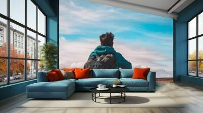 Man Sitting On Rock Looking At View With Backpack On Wall mural