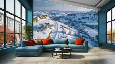 Snow-covered road winding through a valley Wall mural