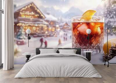 A glass of red drink with an orange slice in it is on a snowy hillside Wall mural