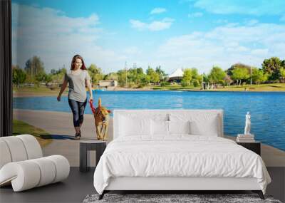 woman and dog walking along lake in park Wall mural