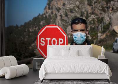 Road maintenance worker during the coronavirus pandemic, on a road with a stop sign and reflective vest Wall mural