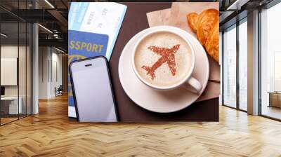 Mug of coffee with an airplane on the foam. Morning coffee with croissant in flight. Paspor and ticket with smrtrfonom Wall mural