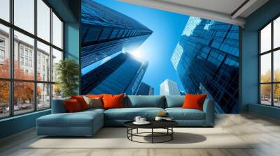 Low angle view of modern skyscrapers with blue glass facades against a clear blue sky. Wall mural