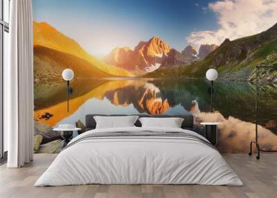 awesome nature scenery beautiful landscape with high mountains with illuminated peaks stones in mountain lake reflection blue sky and yellow sunlight in sunrise amazing nature background Wall mural