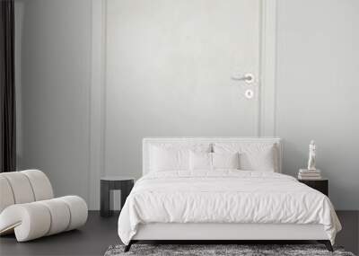 White closed door with silver doorknob on white wall background and parquet floor Wall mural