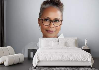 Attractive mature black businesswoman wearing glasses posing looking at the camera on white background Wall mural