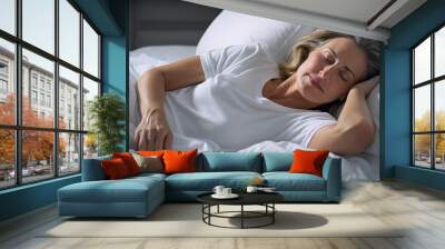 Attractive mature woman sleeping alone in bed Wall mural