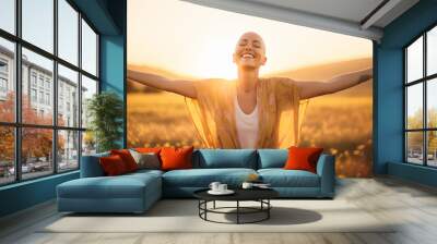 Backlit Portrait of calm happy smiling free breast cancer survivor woman with open arms and closed eyes enjoys a beautiful moment life on the fields at sunset Wall mural