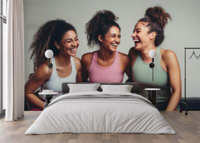 Fun in fitness clothing: Three female friends laughing happily in a sports studio Wall mural