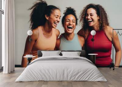 Fun in fitness clothing: Three female friends laughing happily in a sports studio Wall mural