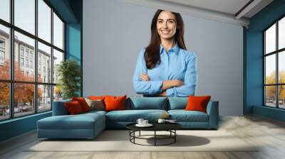 Happy young smiling confident professional business woman wearing blue shirt, pretty stylish female executive looking at camera, standing arms crossed isolated on gray background Wall mural