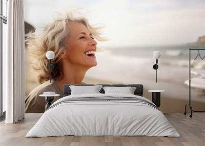 Laughing attractive mature senior woman looking away in the coast Wall mural