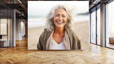 Smiling attractive beautiful caucasian senior mature woman posing at the beach looking at the camera Wall mural