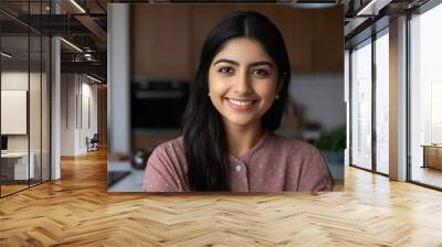 Smiling beautiful young woman sitting at her home kitchen looking at the camera Wall mural