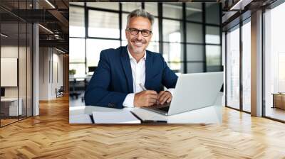 Smiling mature adult business man executive sitting at desk using laptop. Happy busy professional mid aged businessman ceo manager working on computer corporate technology in office Wall mural