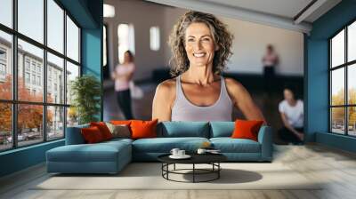 Smiling Mature woman meditating posing at a gym, pilates or yoga studio Wall mural