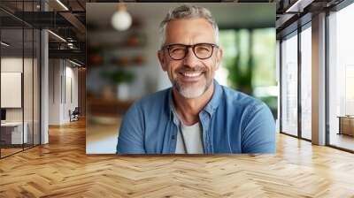 smiling Middle-aged guy with eyeglasses and blue shirt at home Wall mural