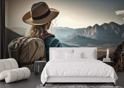 woman with a hat and backpack looking at the mountains and lake from the top of a mountain in the sun light, with a view of the mountains Wall mural