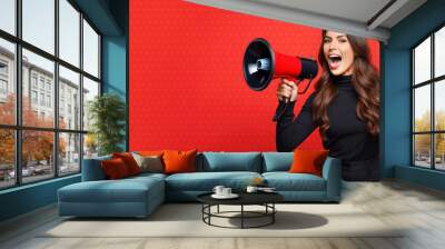 Happy woman announcing Black Friday offers through megaphone on a red background with copy space. Promotional marketing discount and online shopping concept Wall mural