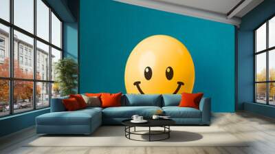 Stock photo of a yellow balloon with smiley face on a blue background Wall mural