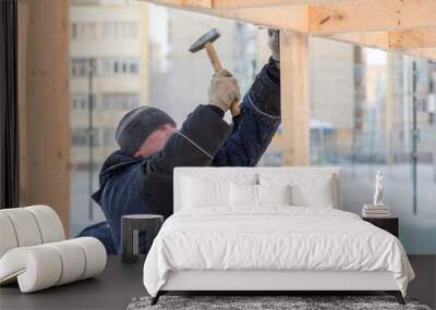 Worker in winter overalls with a hammer in his hand Wall mural