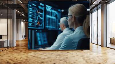 A high-tech workspace shows a woman analyzing data on screens, highlighting teamwork and advanced analytics in a financial or research environment. Wall mural