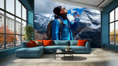 The young hiker stood inhaling canned oxygen on a high ground with a snowy background. Wall mural