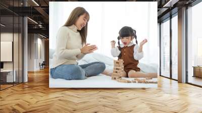 Happy loving family. Asian mother and her daughter child girl playing in bedroom. Wall mural