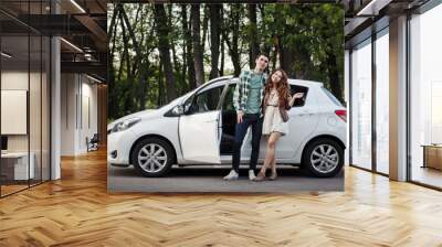 Beautiful young couple on nature near the car Wall mural