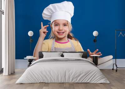 The little girl is cooking and preparing food on blue background Wall mural