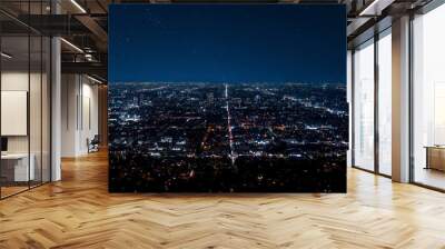 Drone shot of illuminated buildings and skyscrapers with beautiful stars shining in dark sky at modern Los Angeles city during night Wall mural