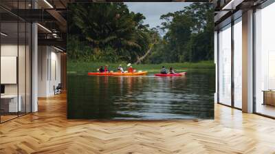 Male and female tourists enjoying rowboat tour exploring along the Tortuguero canal and forest in Costa Rica. Wall mural