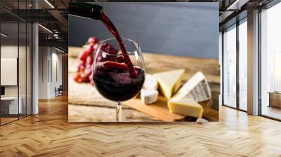 Pouring red wine into the glass against wooden table Wall mural