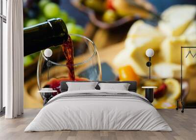 Pouring red wine into the glass in the background composition of appetizers Wall mural