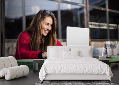 smiling young woman working on laptop at outdoor coffee shop table Wall mural