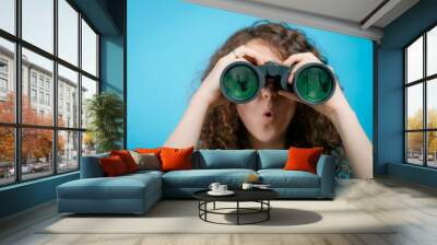 portrait of young girl looking through a binoculars Wall mural