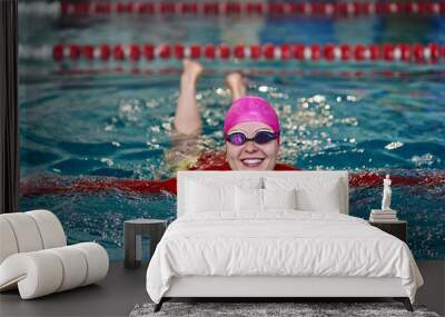 Portrait of a smiling woman swimmer in red yellow swimsuit in the pool after the completion of training. Wall mural