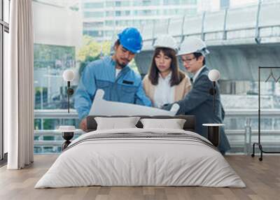 Civil engineer teams meeting working together wear worker helmets hardhat on construction site in modern city. Foreman industry project manager engineer teamwork. Asian industry professional team Wall mural