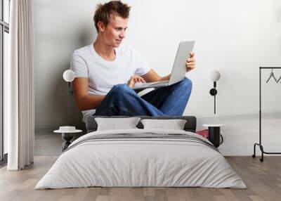 A handsome young man with laptop on grey background Wall mural