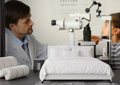 Adult male doctor examing small girl patient Wall mural